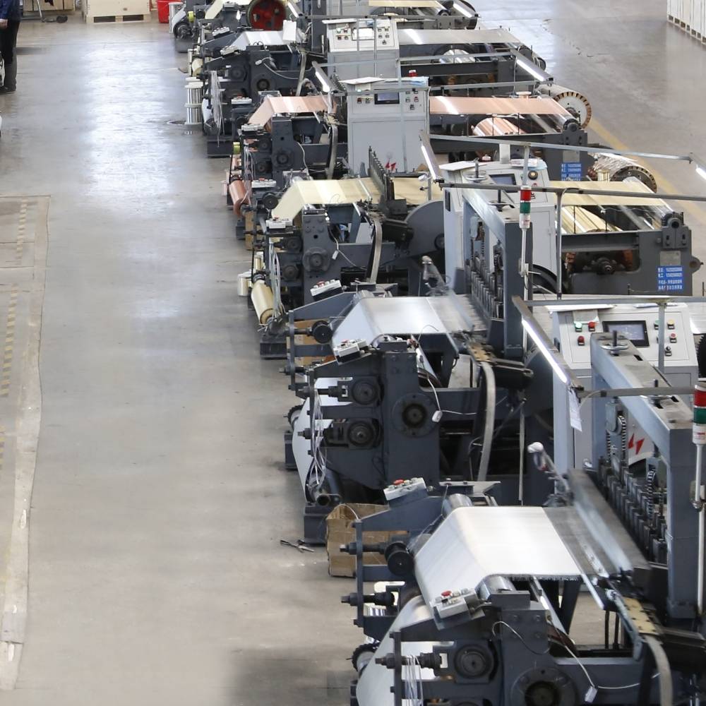 Dozens of weaving machines are placed in the workshop.