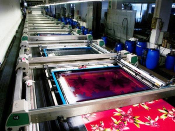 The machine is printing patterns on textile fabric