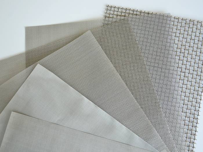 A roll of stainless steel woven mesh laid flat on a white background